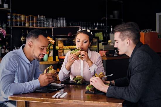 Tre personer sitter och äter på veganska mackor på en pub
