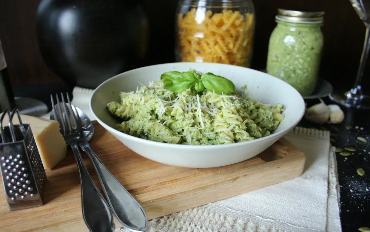 Broccolipesto med pasta i en vit tallrik på en skärbräda