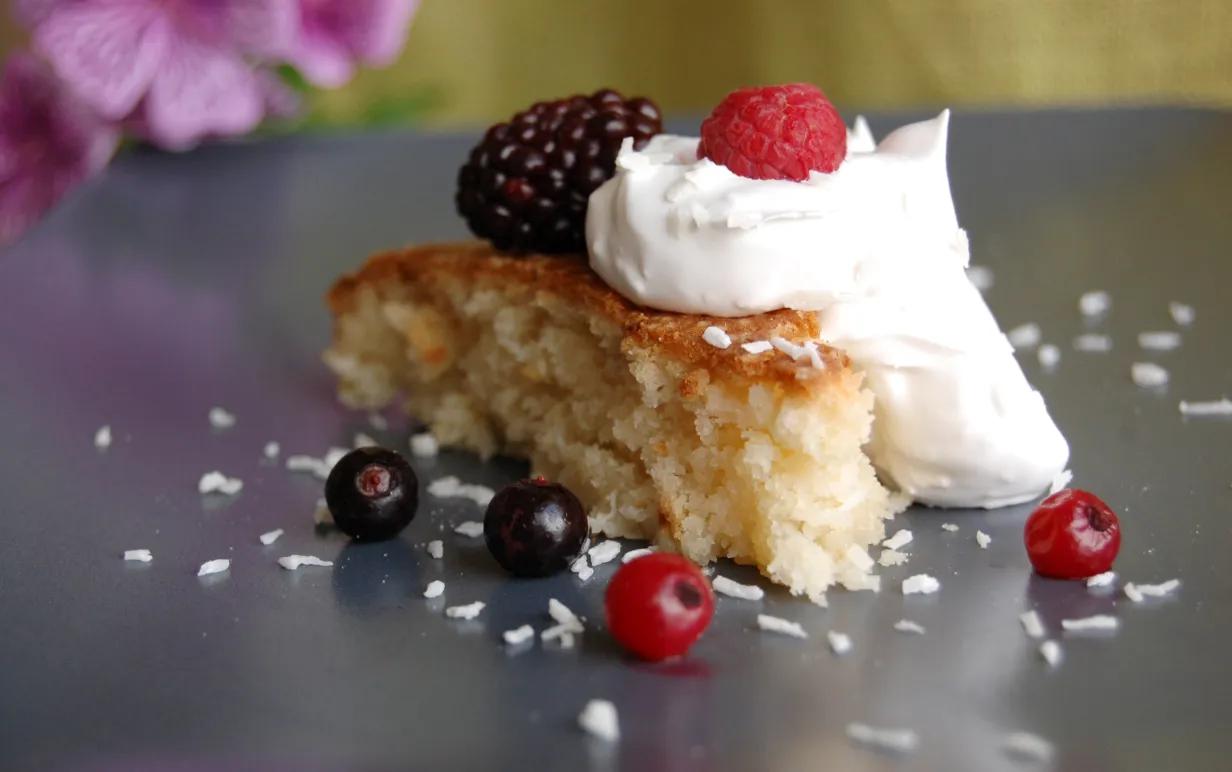 Kokoskaka med grädde, dekorerad med björnbär, hallon, svarta och röda vinbär.