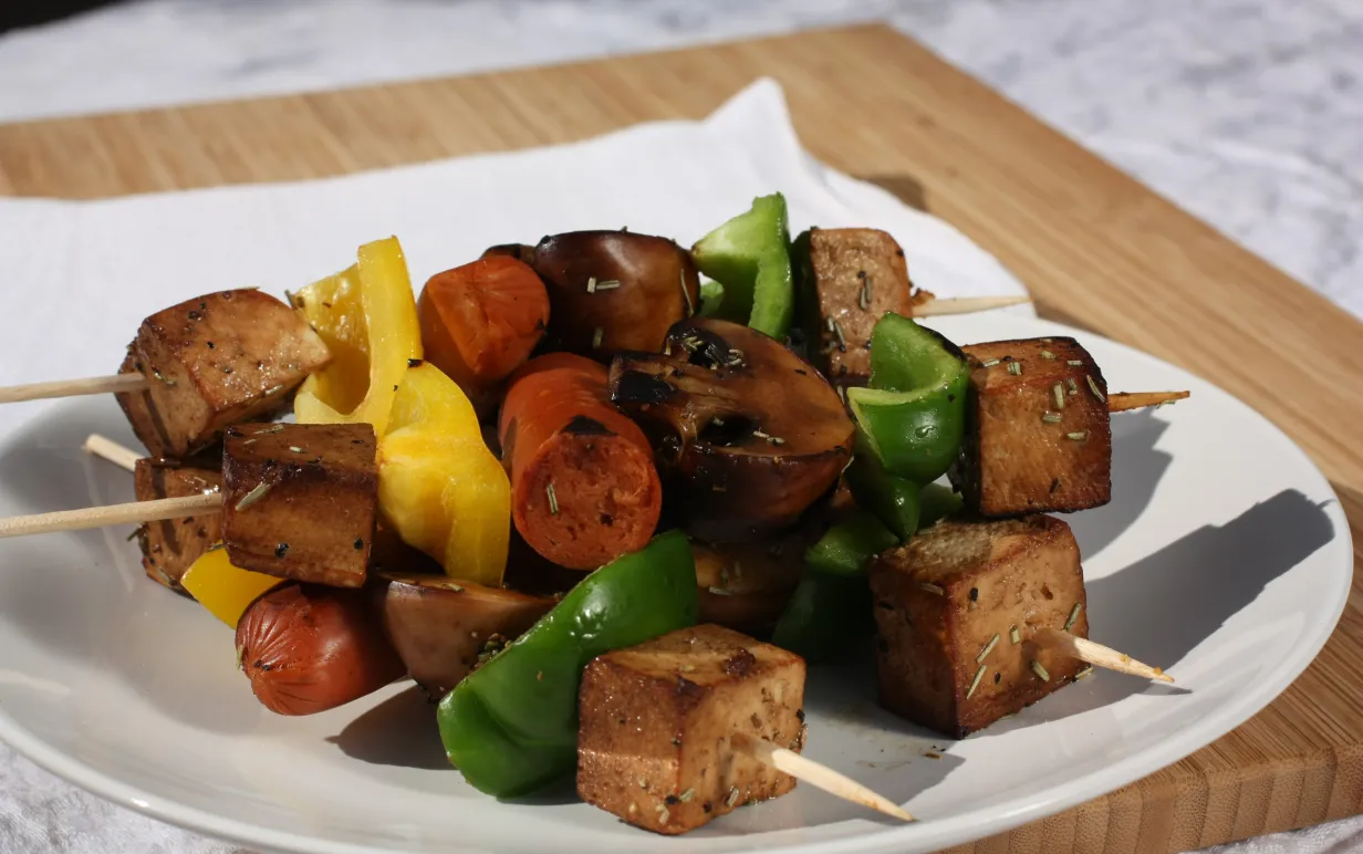 Grillspett med svamp, paprika, tofu och kryddig korv på en vit tallrik