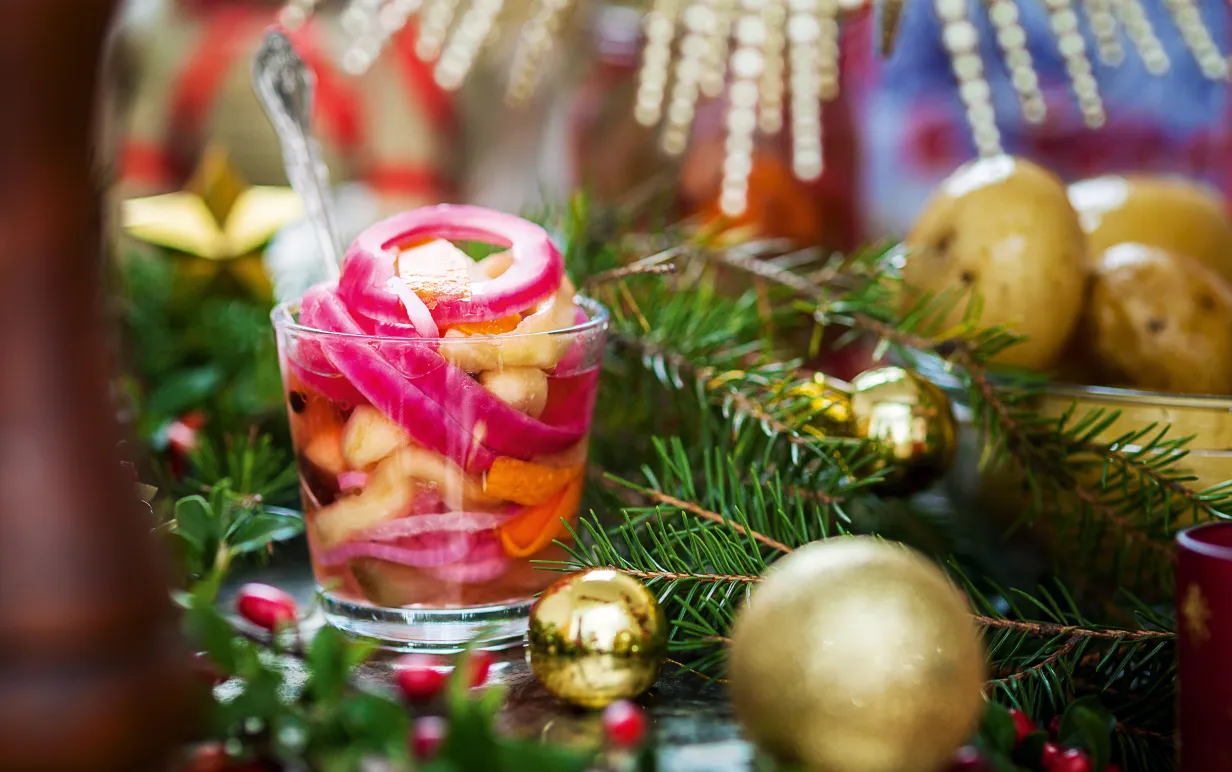 Bild på vegosill i genomskinlig behållare intill en guldfärgad julkula