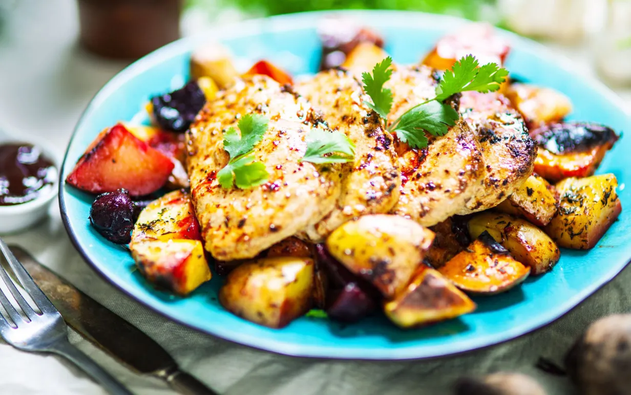 Ugnsrostade grönsaker och scallopini på en turkos tallrik