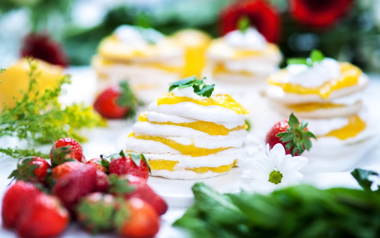 Marängtårta med mango curd, dekorerad med jordgubbar och citronmeliss.
