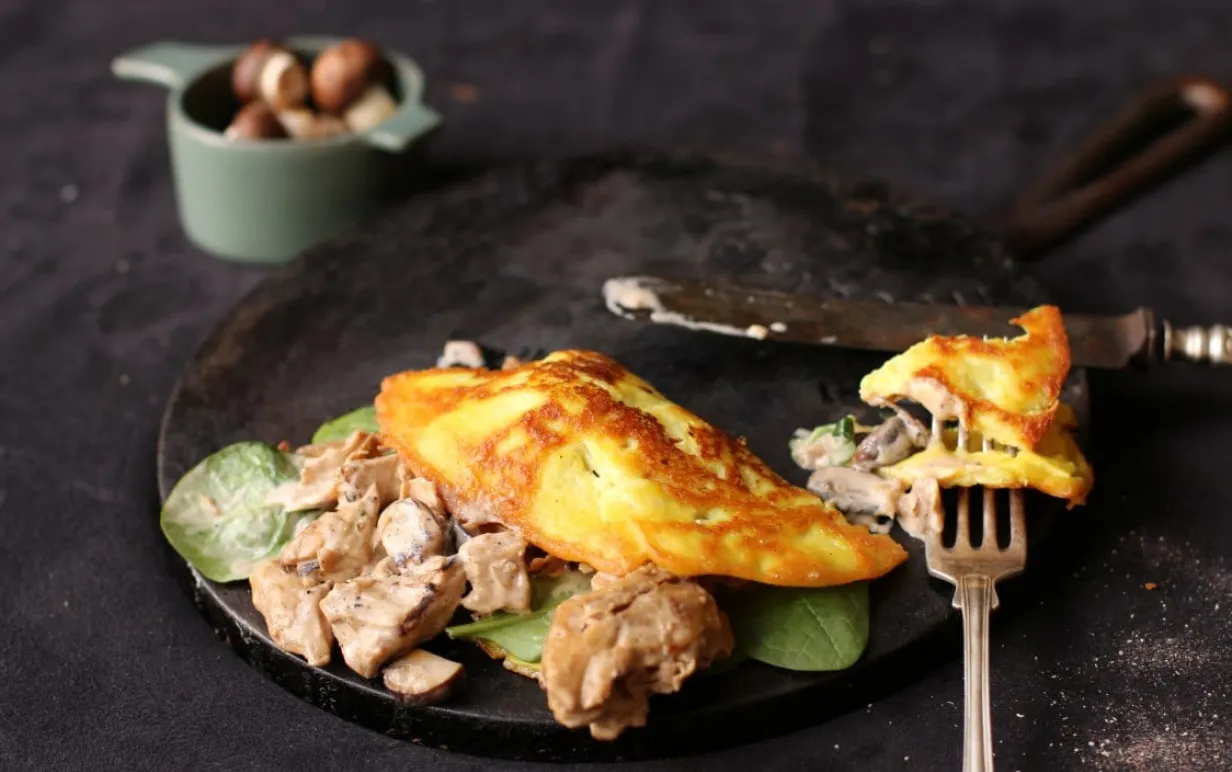 Omelette med oumph på en svart tallrik på ett svart bord.