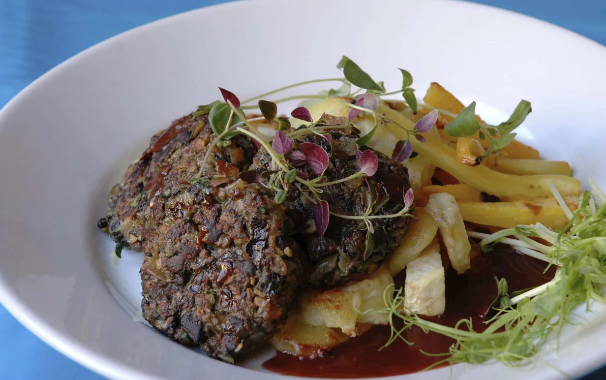 Veganska svampbiffar med sås och potatis på en vit tallrik.