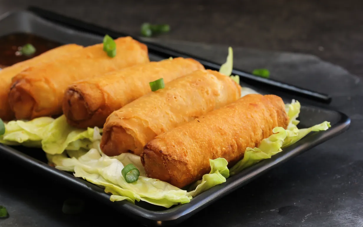 Fem vårrullar på en svart tallrik.