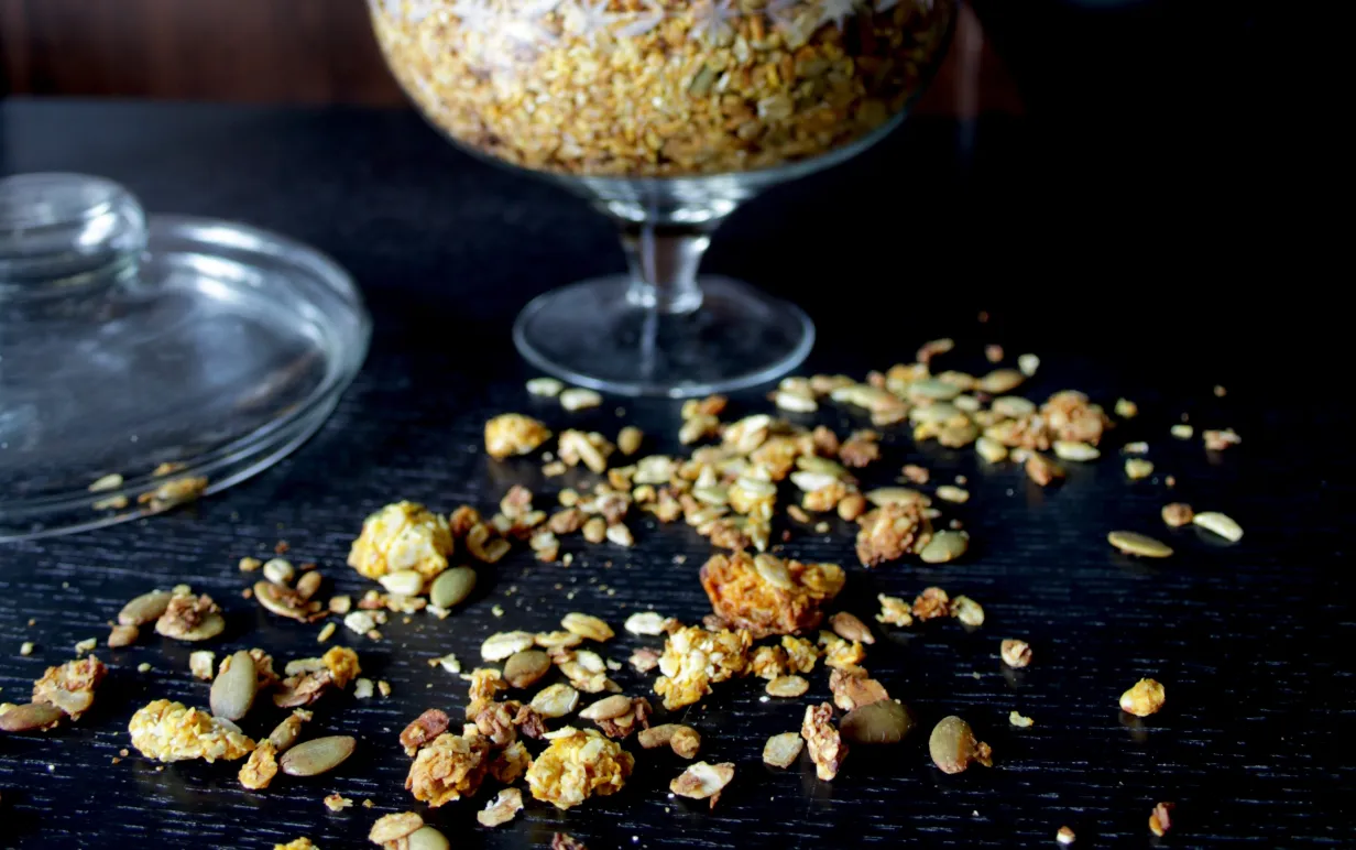Saffransgranola i en glasbägare på ett mörkt bord.