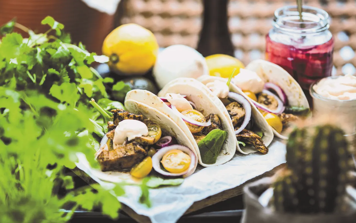 Fyra tortillas fyllda med veganska bitar och grönsaker på ett bord