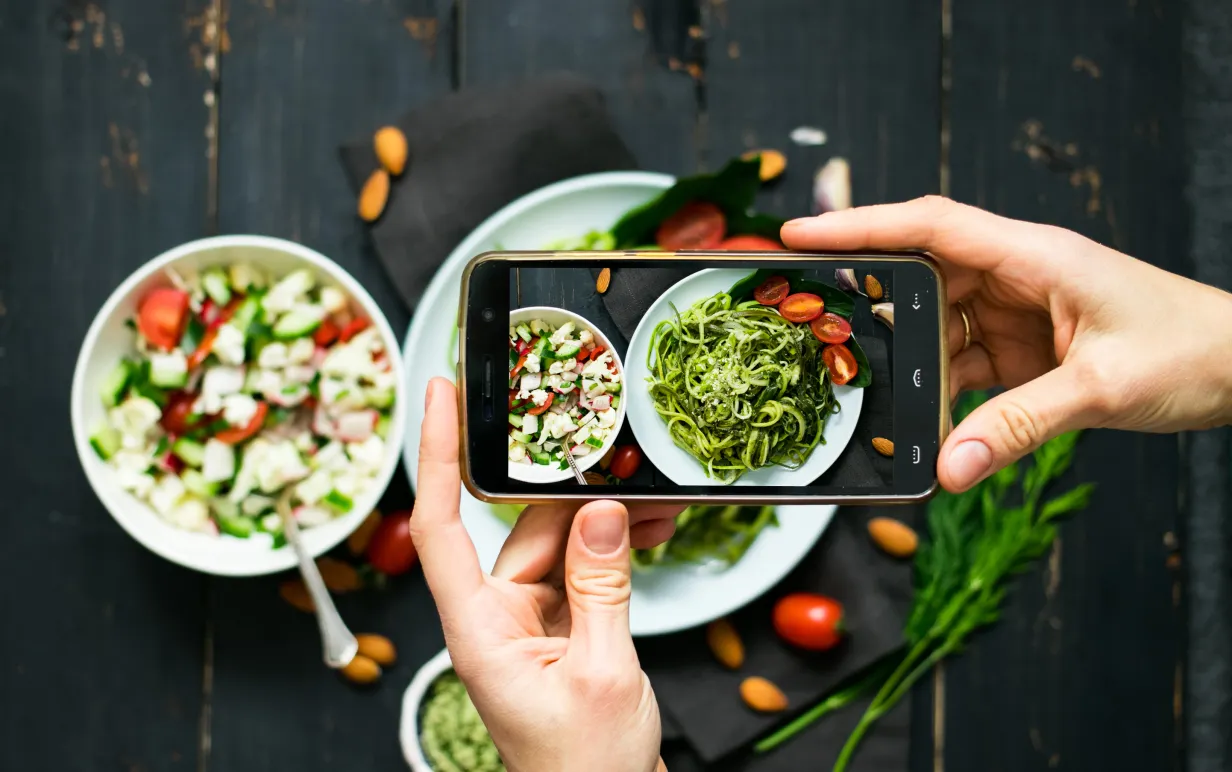 Person tar bild på sin tallrik med mat med sin mobiltelefon