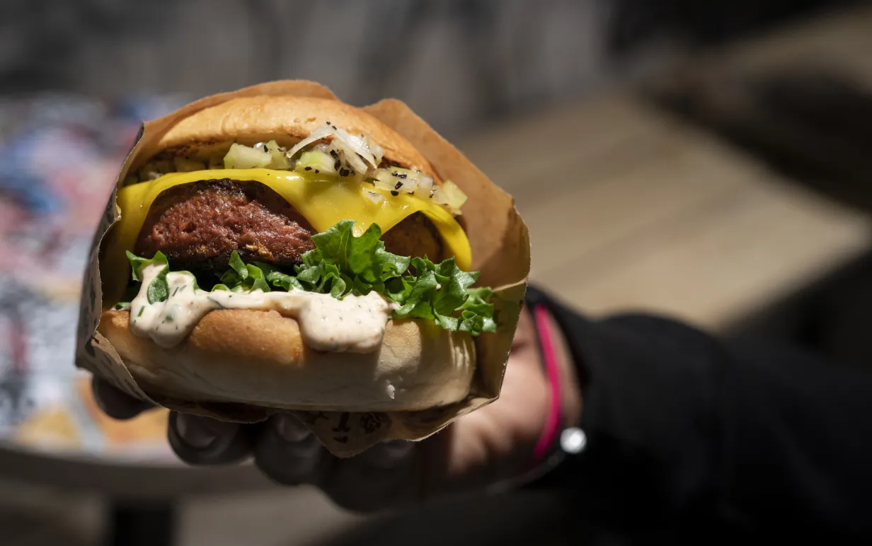 Person håller upp en vegansk burgare