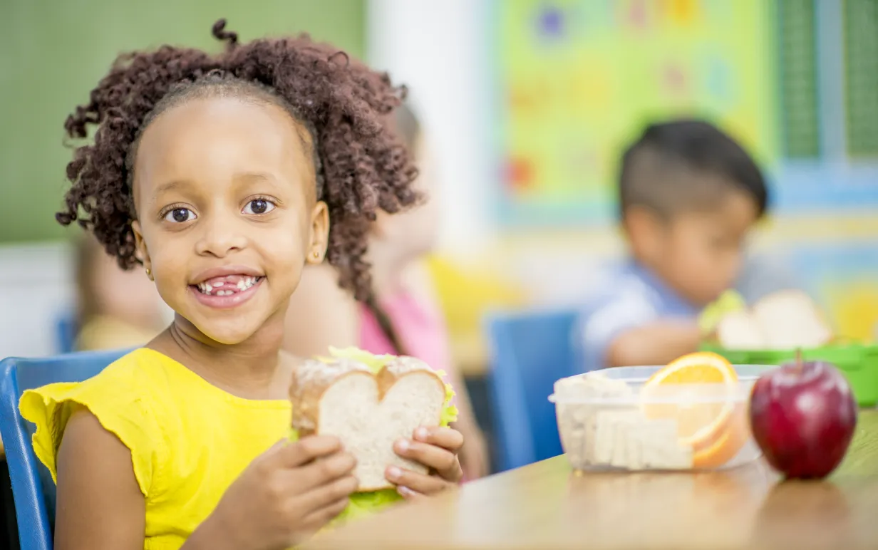 Barn sitter och äter macka