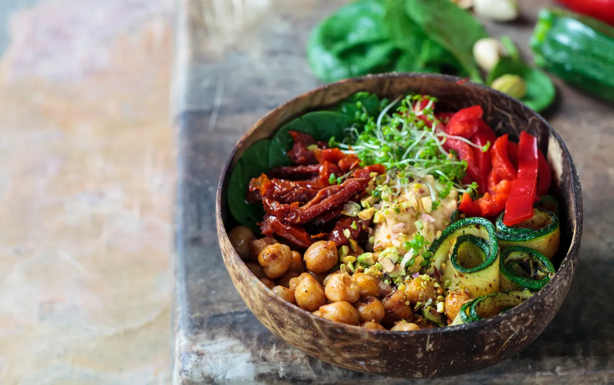 En vegansk bowl med hummus, paprika, kikärtor, krasse bland andra grönsaker.
