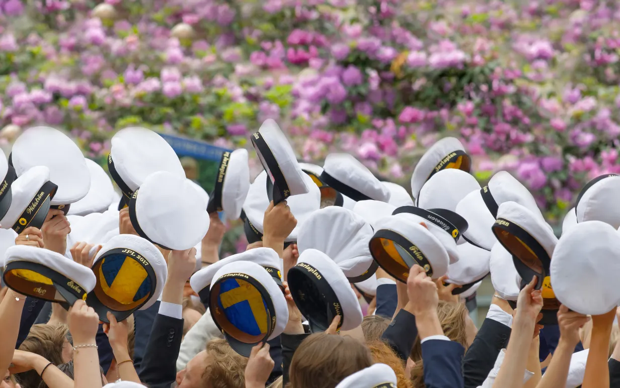 Personer som håller i studentmössa i över huvudet