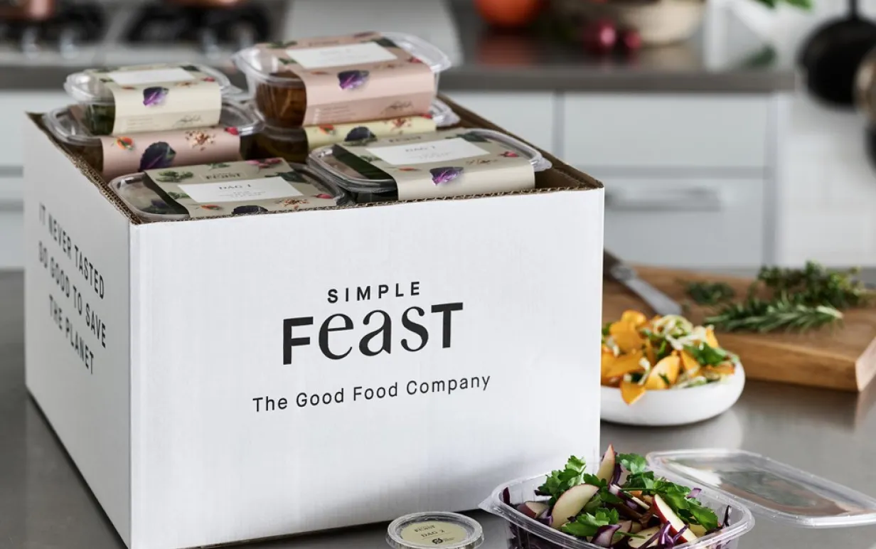 En box fylld av växtbaserade rätter från Simple Feast på en köksbänk.