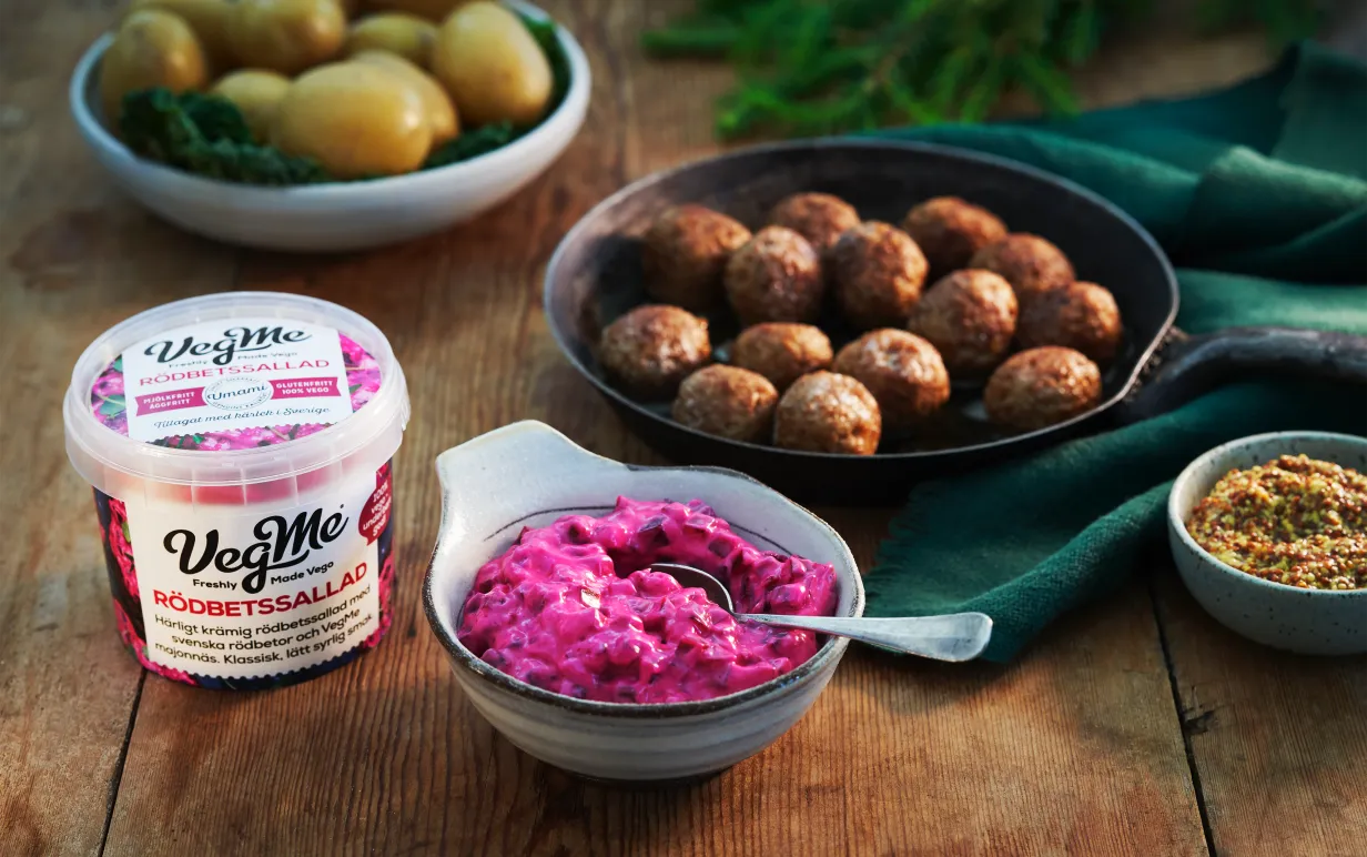 Förpackning på vegansk rödbetssallad från Vegme på ett bord intill vegobullar