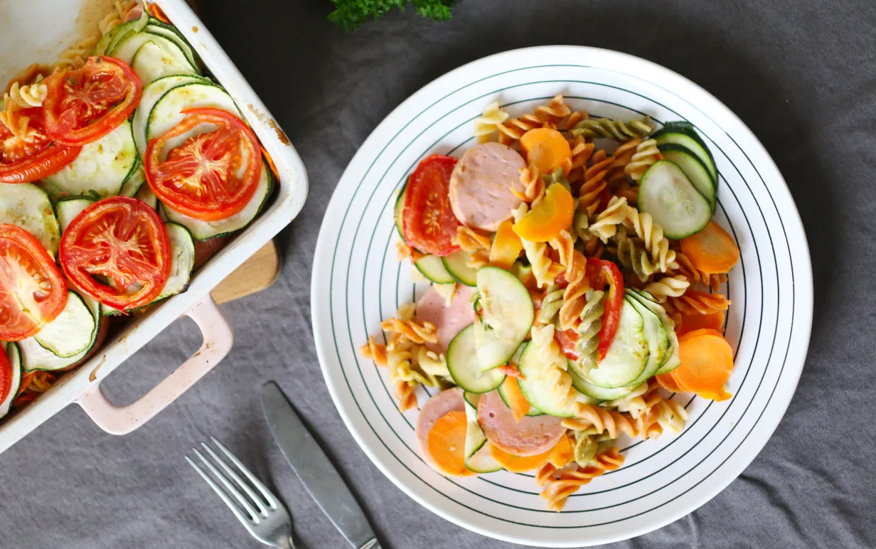 Vegansk pastagratäng på en tallrik intill en form med mer pastagratäng