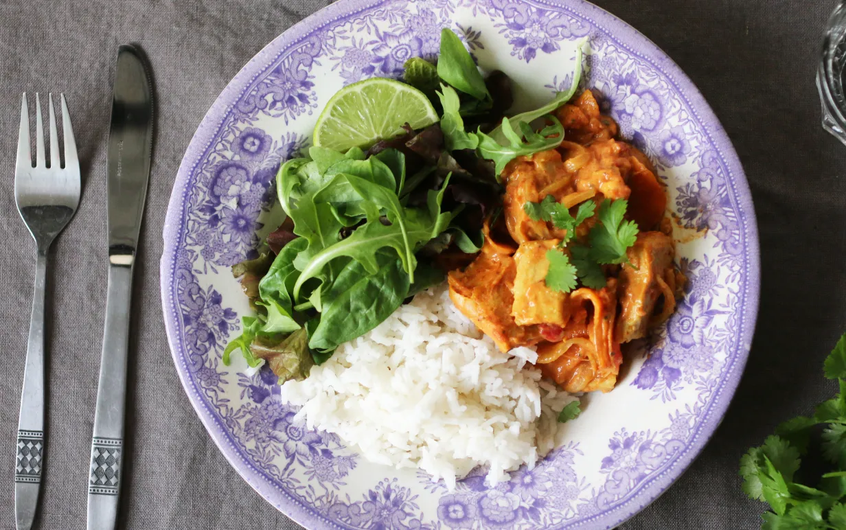 Tallrik med vegansk tikka masala, ris och grönsaker