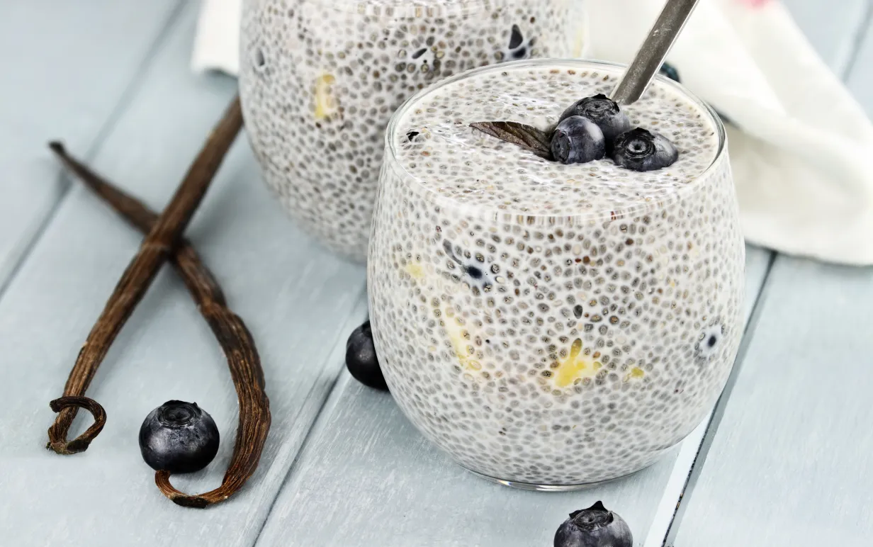 Chiapudding i ett glas med några blåbär på ett bord.