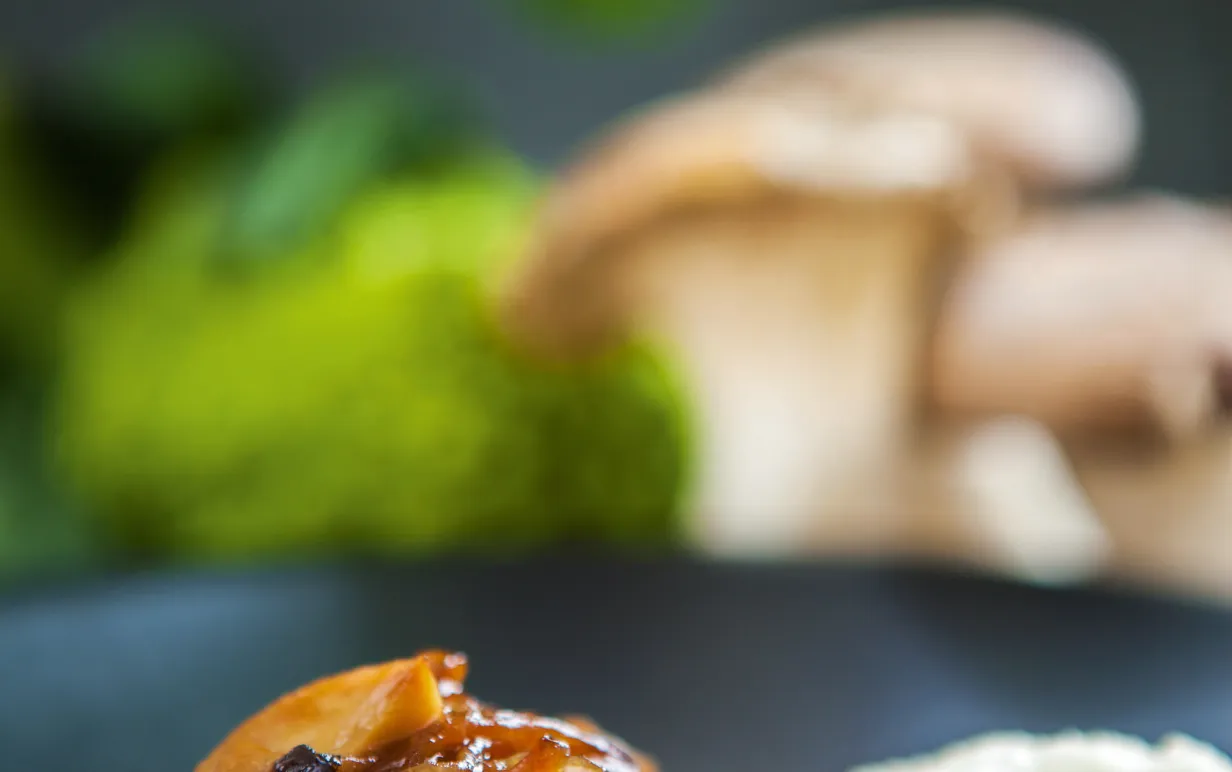 Smörstekta svampar med karamelliserad lök och blomkålspuré på en tallrik