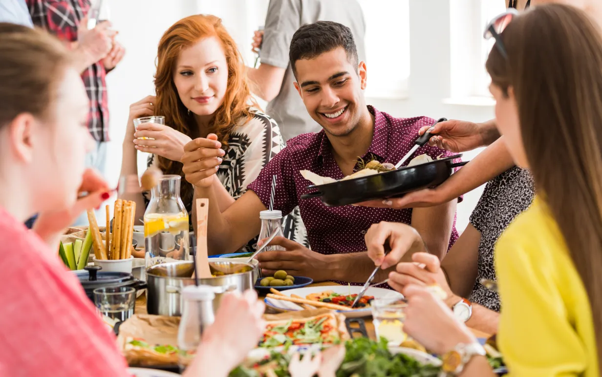 Ett gäng vänner samlade kring ett bord och äter veganskt mat