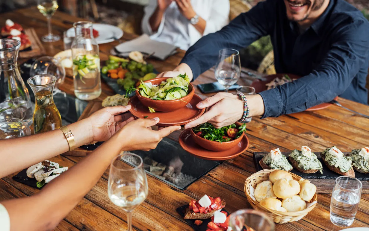 Flera personer runt ett bord delar på veganska rätter