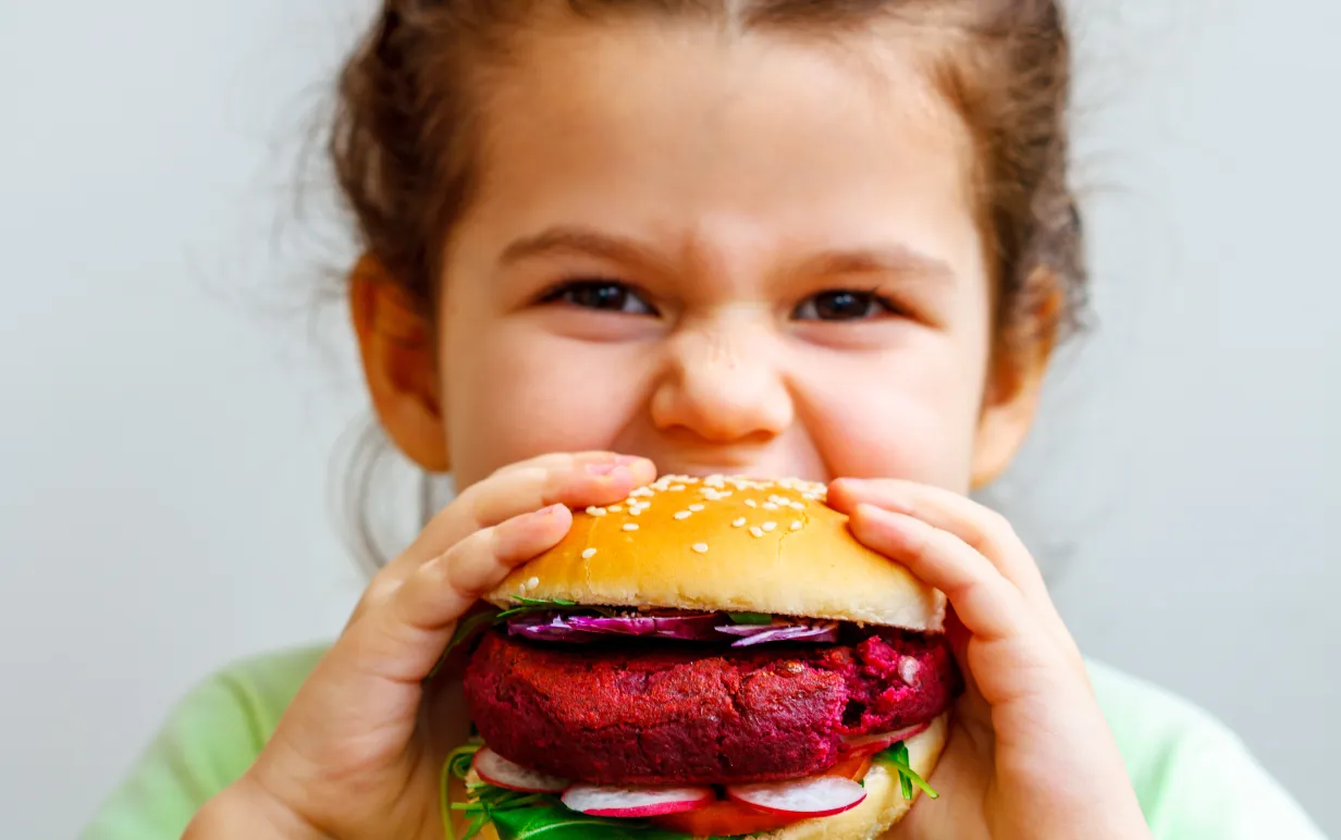 Ett barn tar en tugga av en vegansk burgare