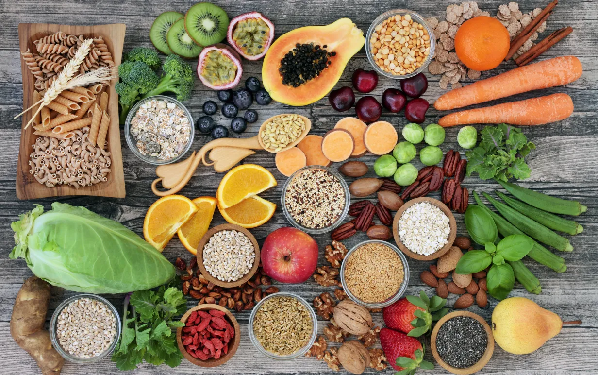 Veganska baslivsmedel, främst frukt och grönt, fotat ovanifrån på bordsyta.