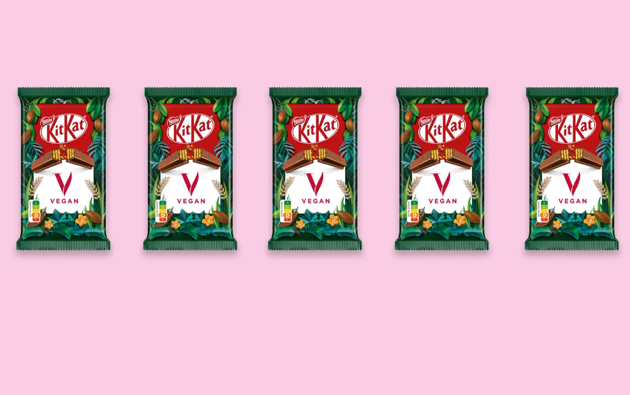 Fem veganska KitKat vegan uppradade mot en ljusrosa bakgrund.