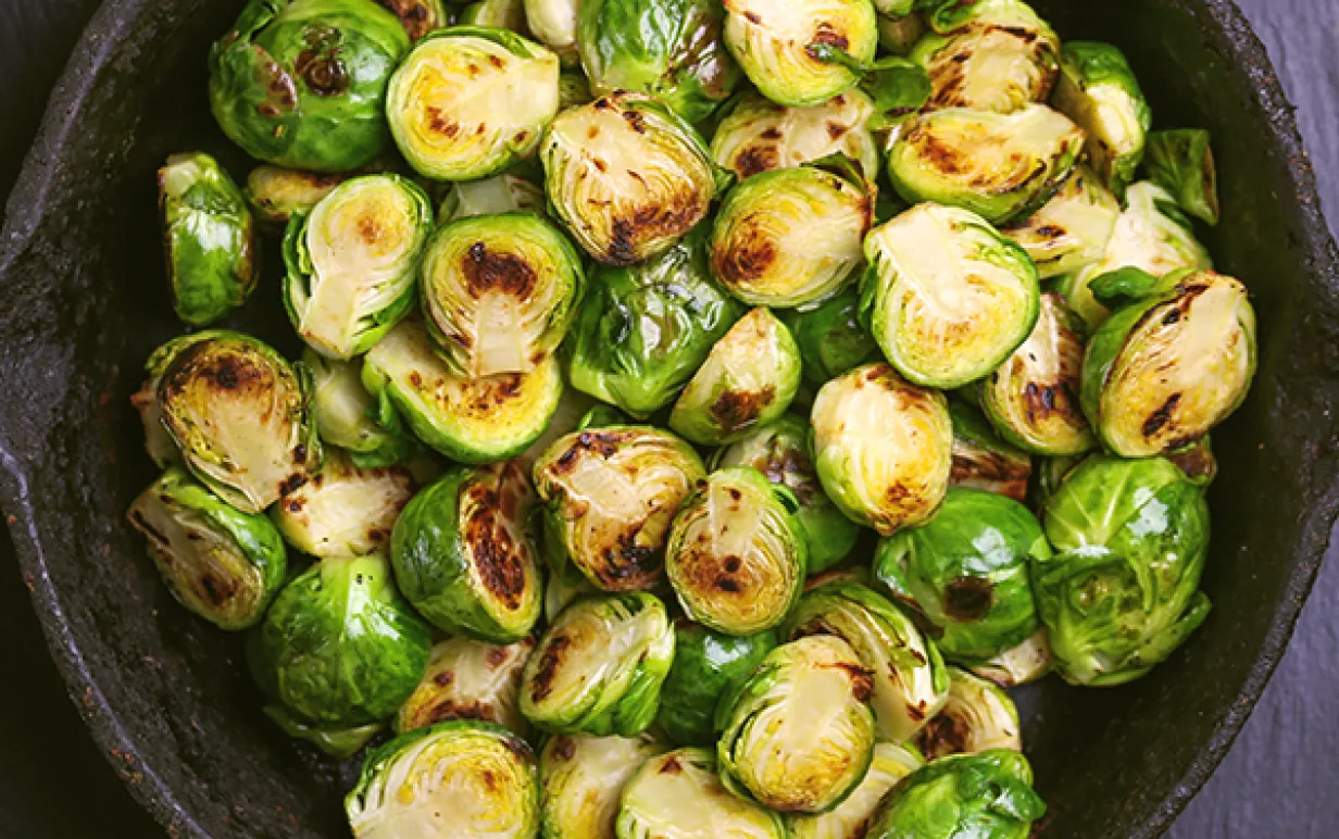 stekt brysselkål i en svart serveringsskål på ett mörkt bord
