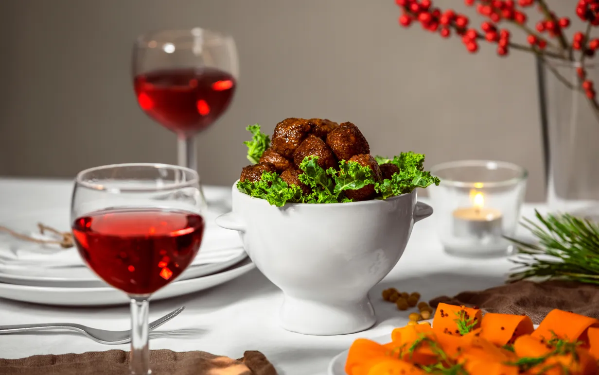 Veganska köttbullar i en vit keramikskål på ett uppdukat julbord.