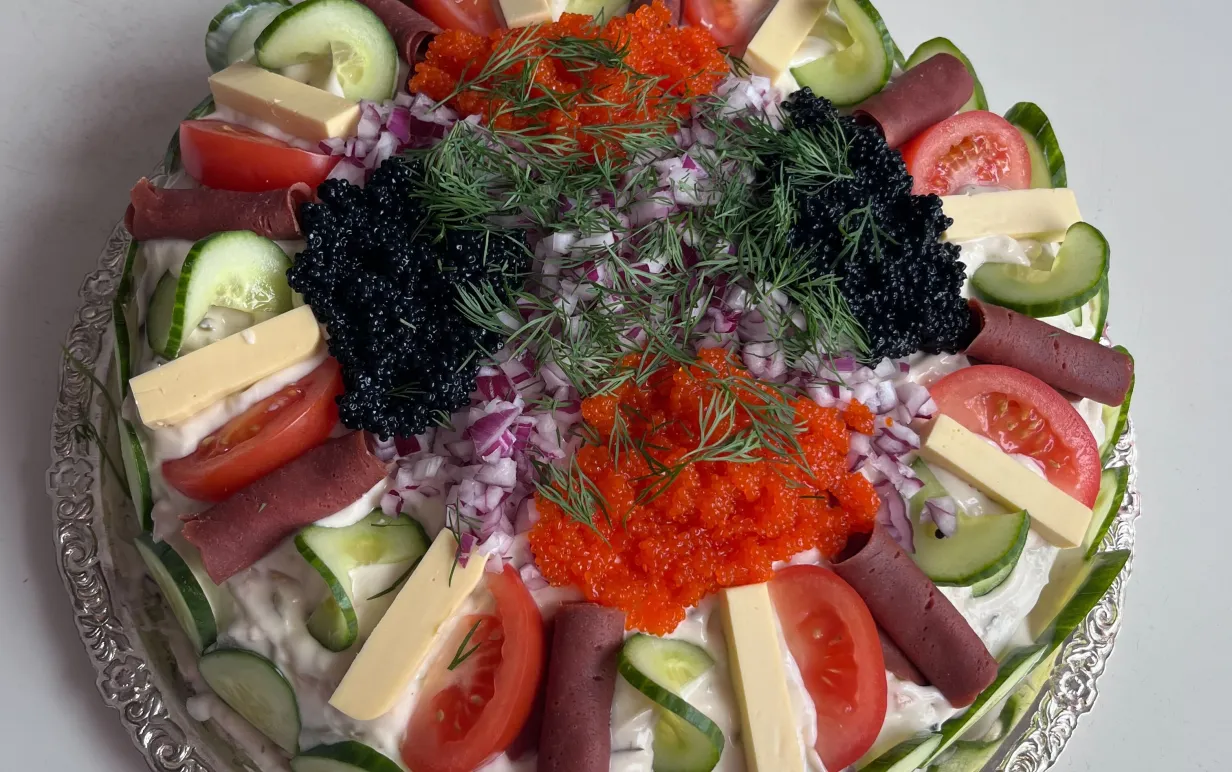 Vegansk smörgåstårta i rund form på ett silverfat.