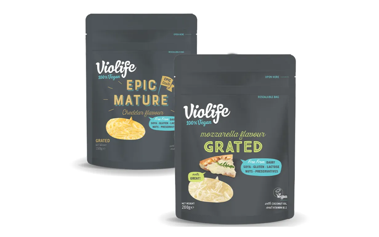 Två påsar riven vegansk ost mot en vit bakgrund.