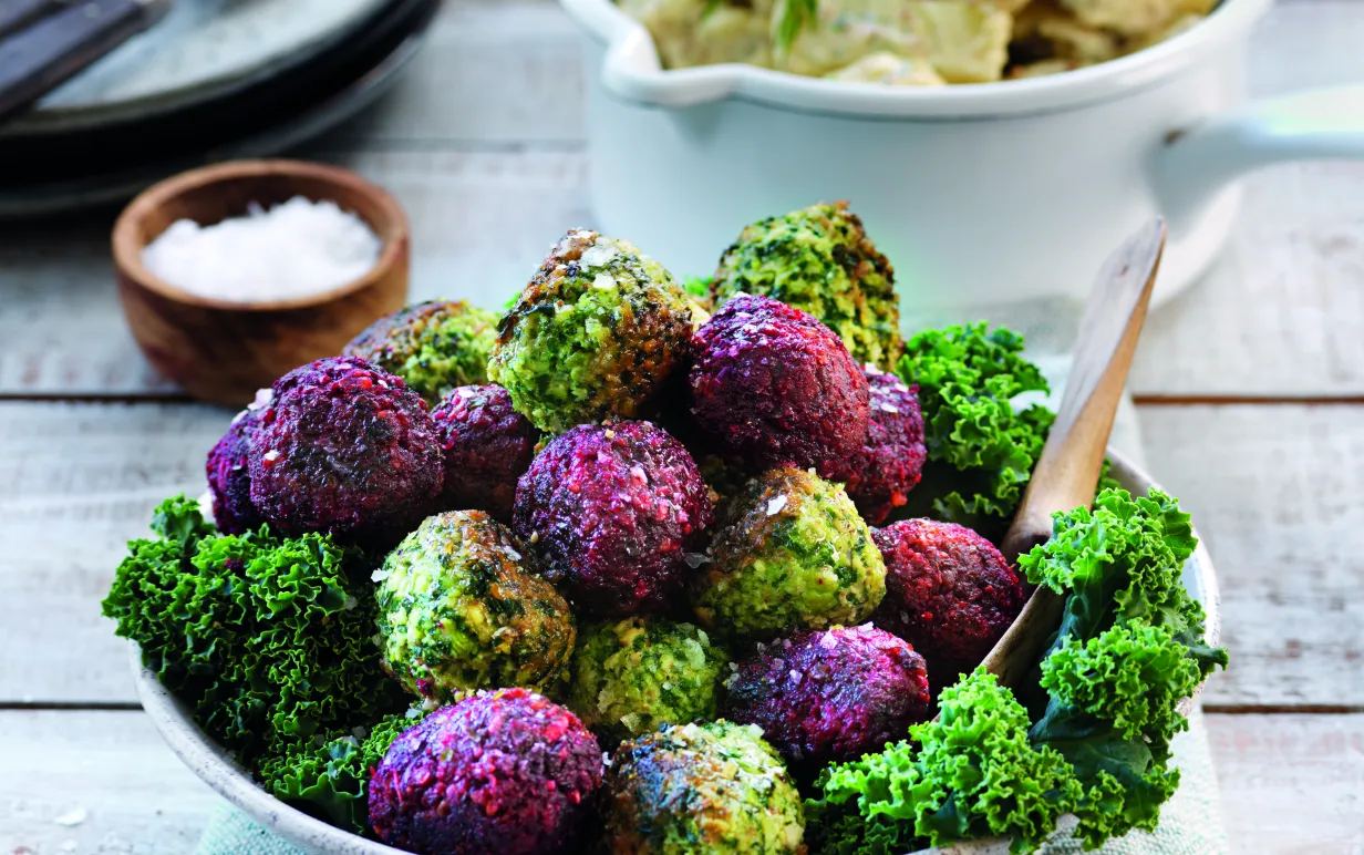 En skål med gröna och lila bollar på grönkål och rödbetor