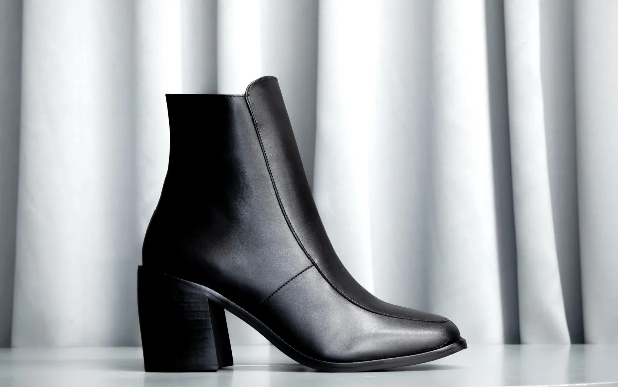 Stövlett i veganska skinn mot ett ljusgrått draperi