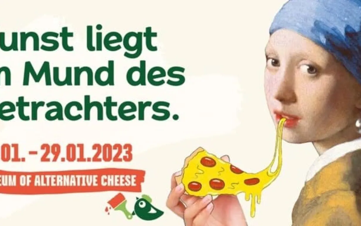Flickan med pärlörhänget äter en pizzaslice med veganost på