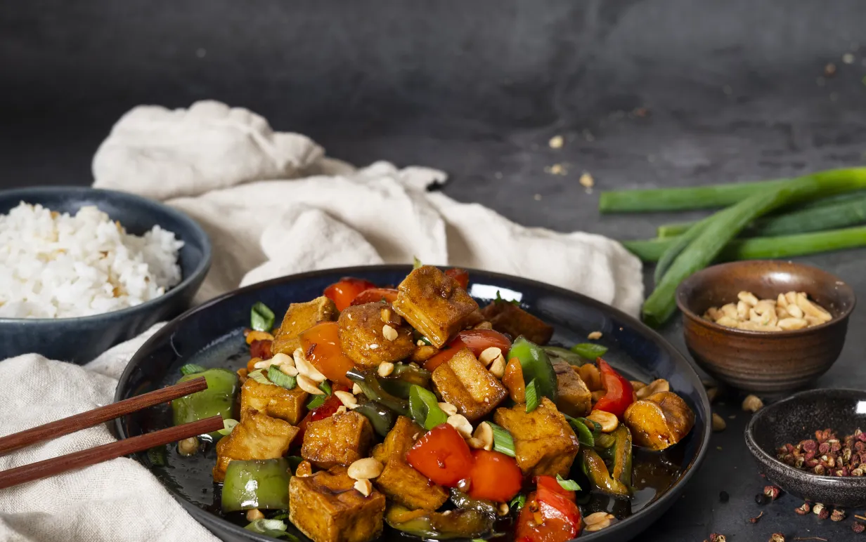 Kung Pao rätt i djuptallrik på en kökshandduk mot en mörkgrå bakgrund