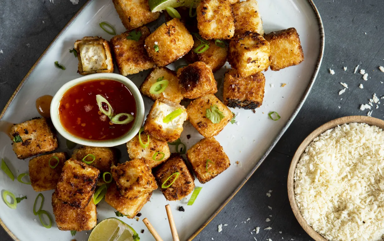Panerad tofu på ett ljust serveringsfat mot en mörk bakgrund.