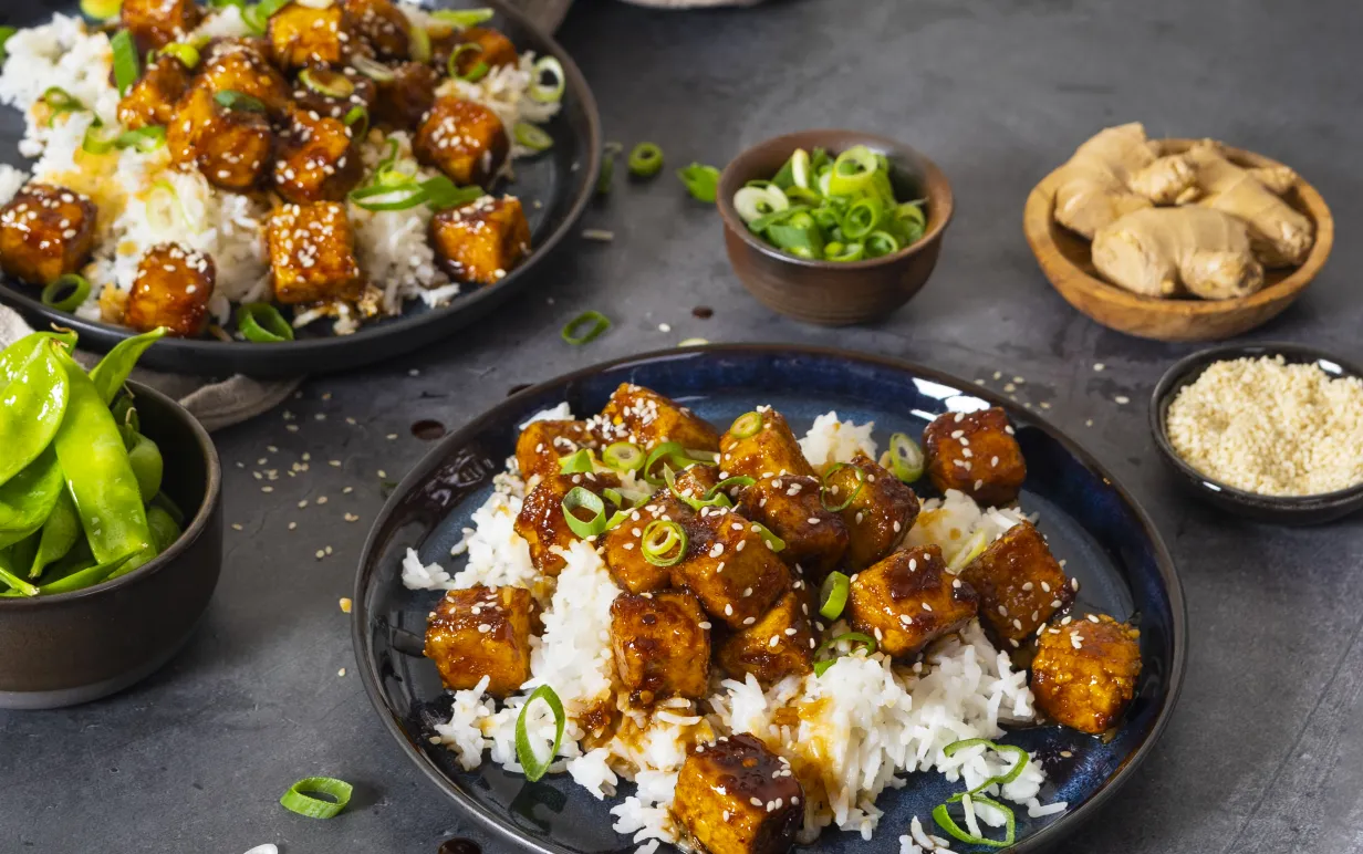 Två djuptallrikar med general tso tofu på ett mörkgrått bord