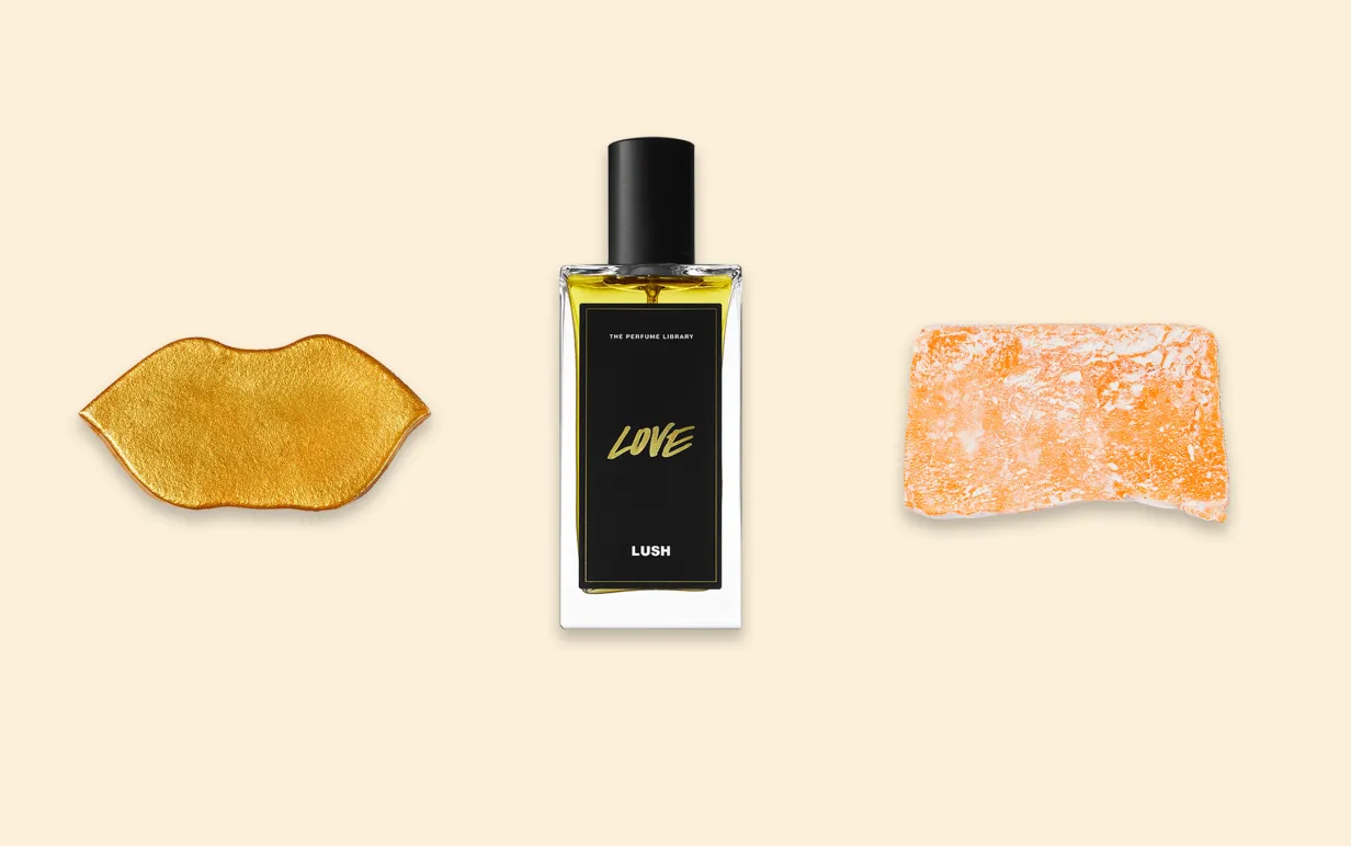 En läppmask i guld, en parfymflaska och en ljusorange tvål uppradade mot en ljusgul bakgrund