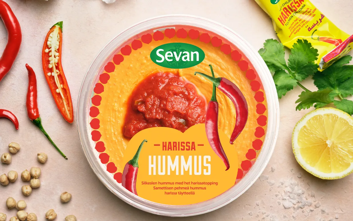En burk med hummus på ett bort med citron, mynta, vitlök och kikärtor runt