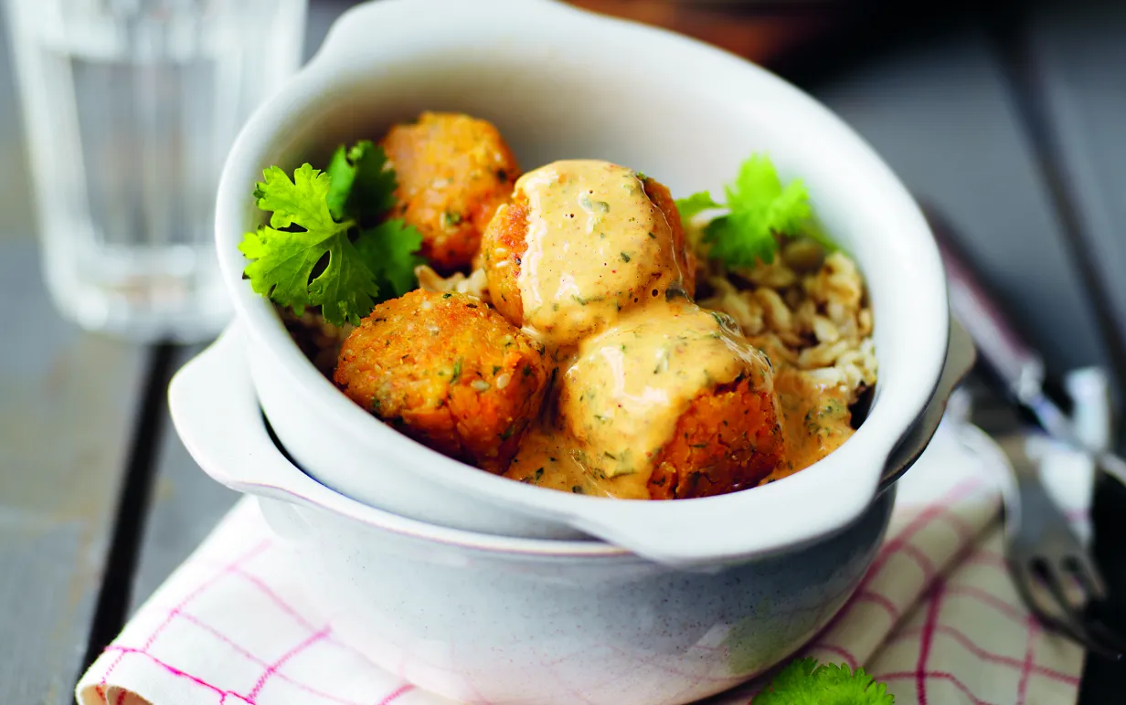 Majsbollar i en vit skål på en kökshandduk på ett träbord