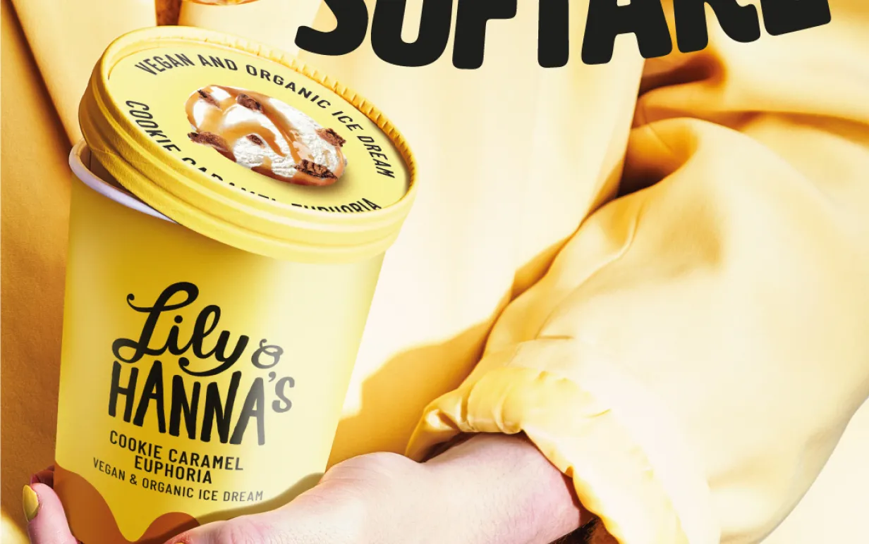 Kvinna i gula kläder som håller en gul glassbytta med en sked med glass i handen