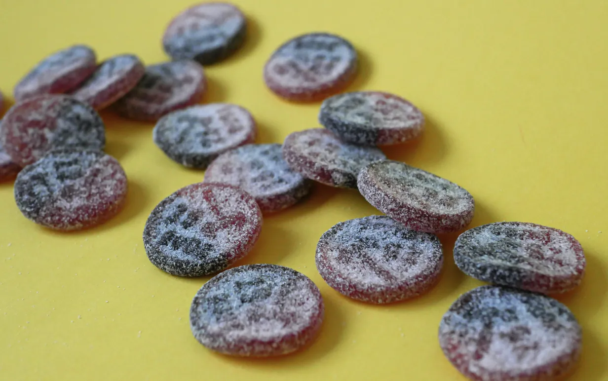 utspridda lakritsgodisar på ett gult underlad