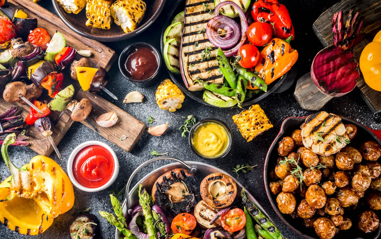 Ett bord fullt med grillade grönsaker och veganska tillbehör