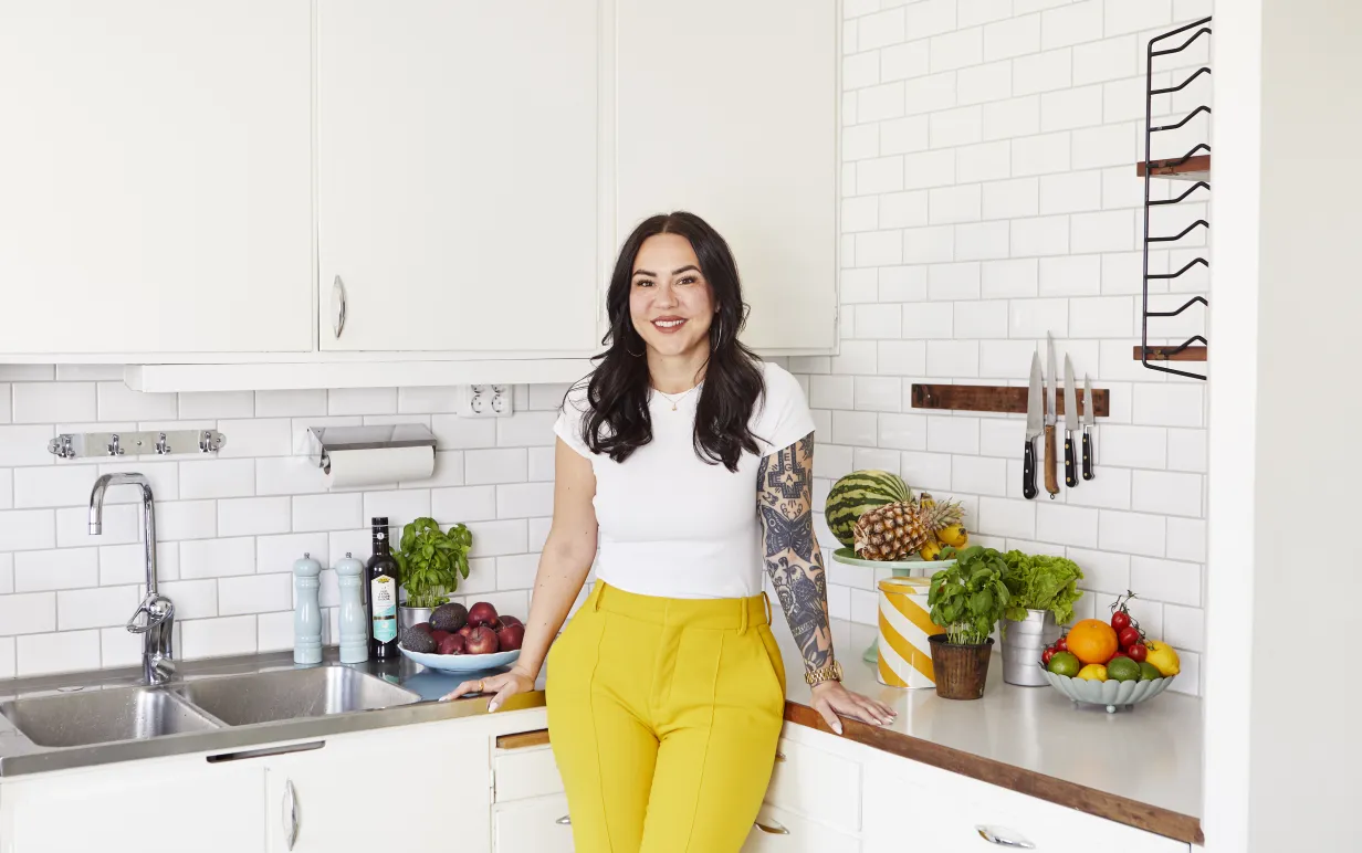 En kvinna som står lutad en köksbänk i ljusa färger