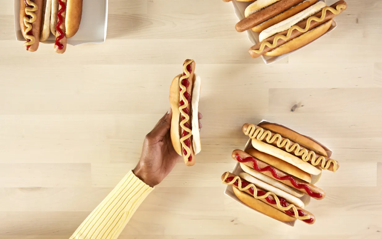 9 veganska varmkorvar och en hand mot ett bord i björk