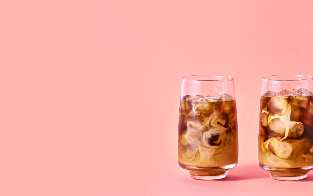 Iskaffe med växtdryck mot en ljusrosa bakgrund