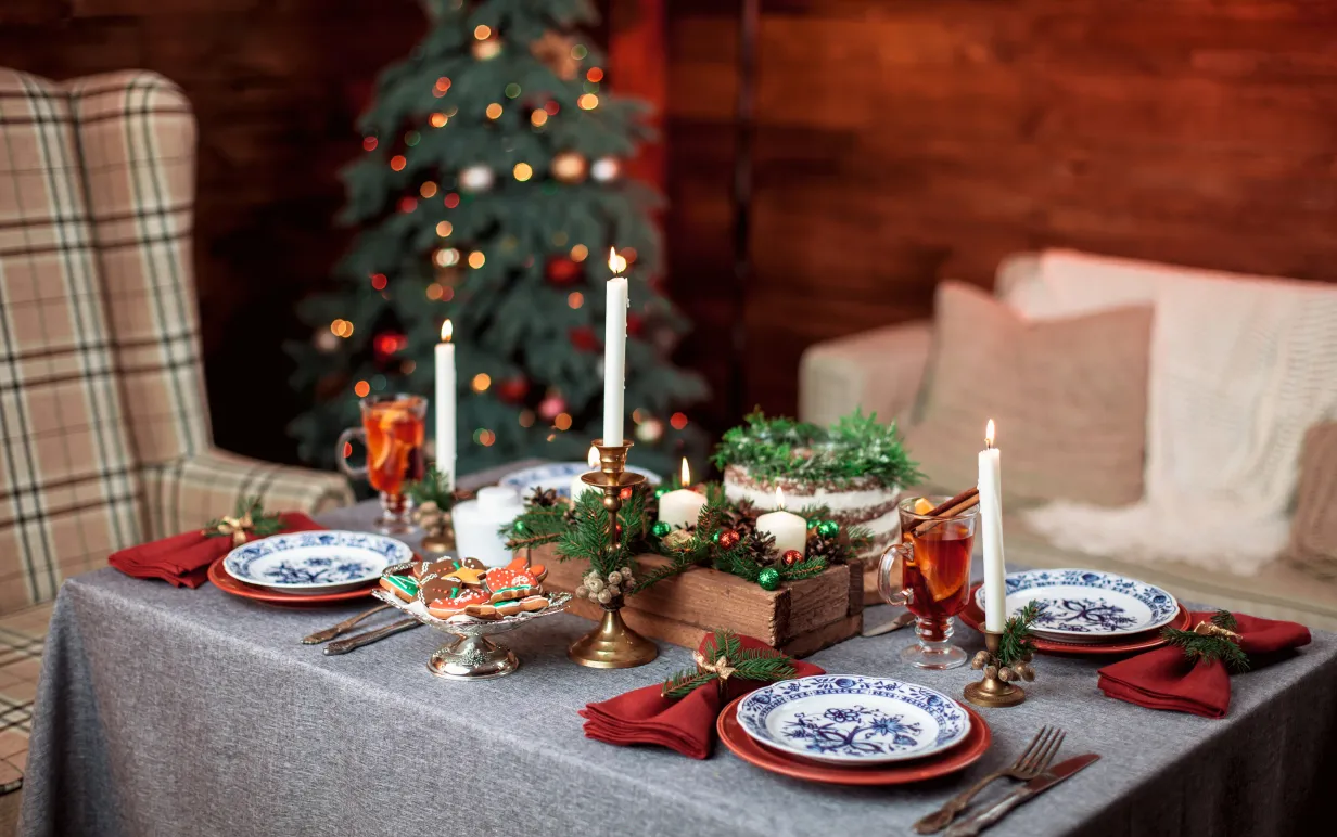 Ett uppdukat bord för 4 personer med en julgran i bakgrunden