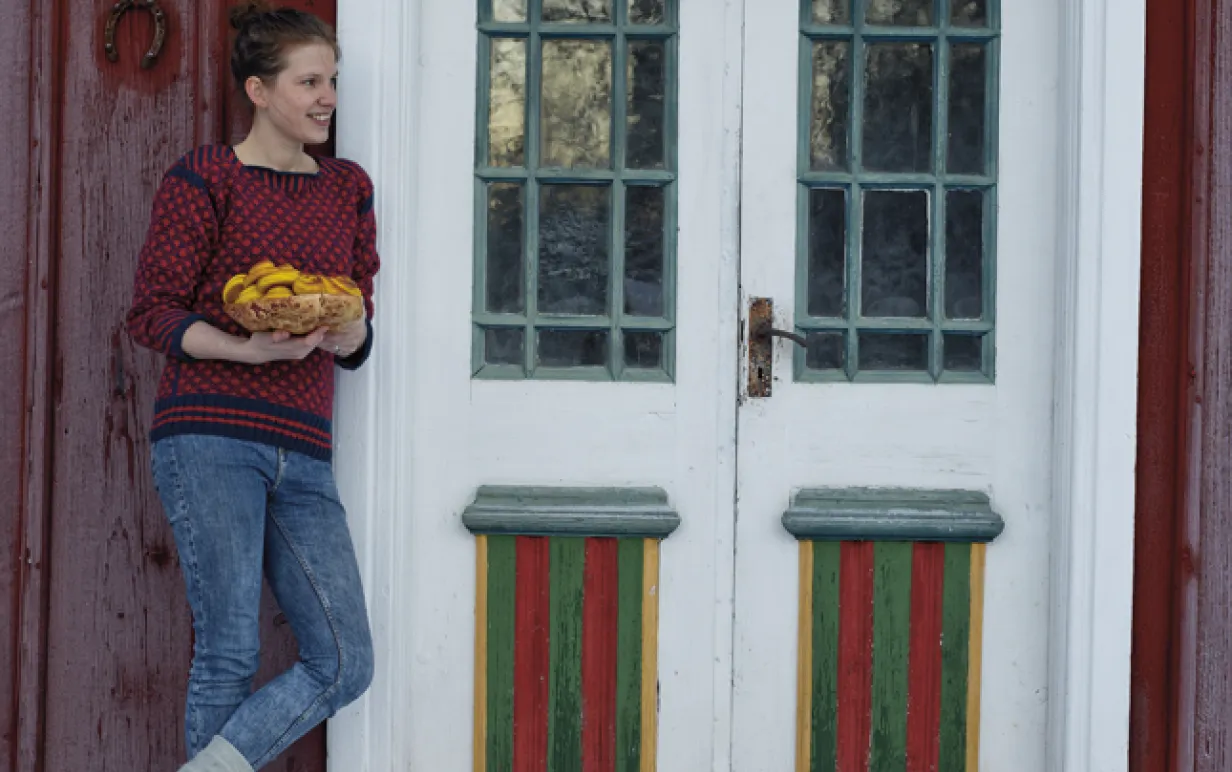 Kvinna som står lutan mot en röd vägg på ett hus