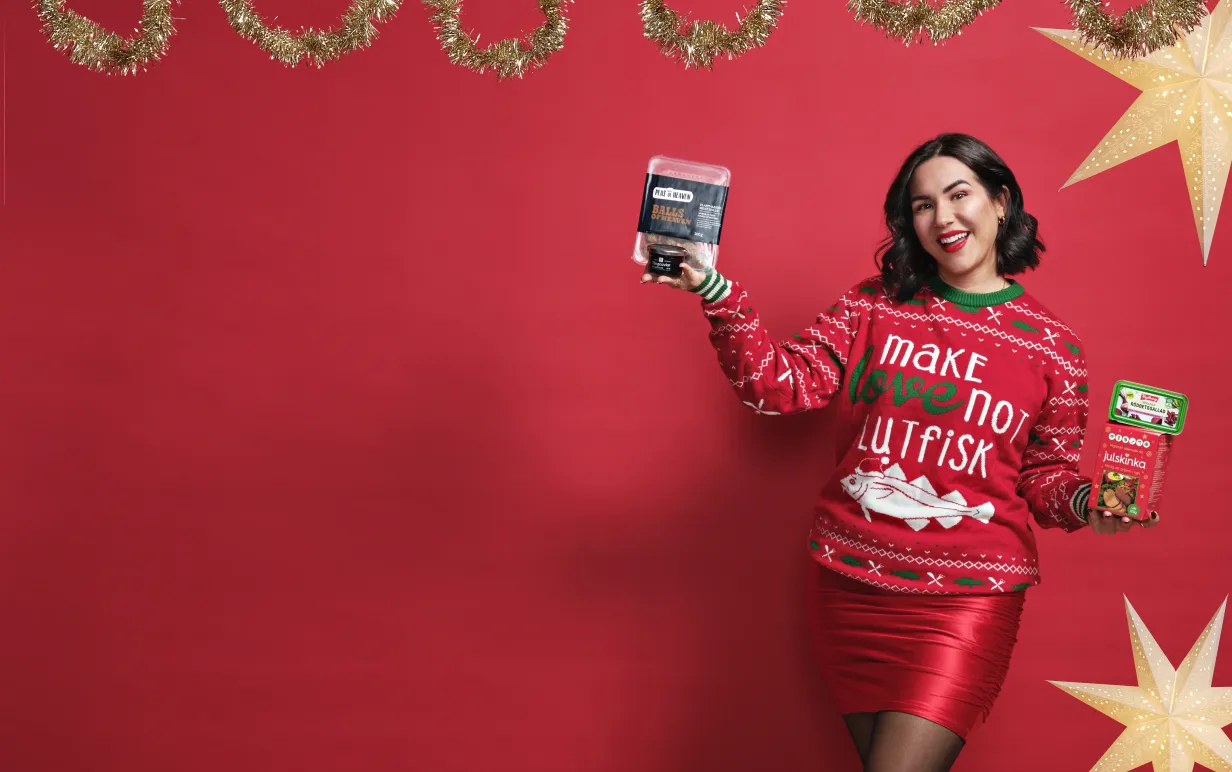 Mörkhårig tjej i röd jultröja mot en röd bakgrund hållandes i julmat